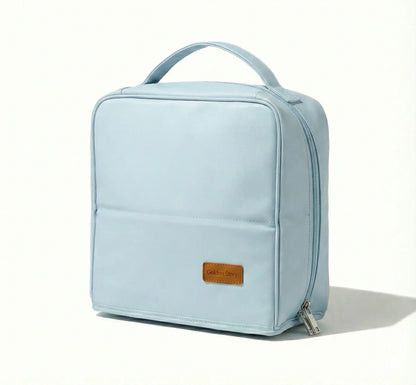 Front view of the light blue Sunday Status stand-up travel makeup bag on a clean white background, highlighting its structured square shape, top handle, and minimalist pastel design